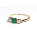 An emerald and diamond three stone ring, the emerald-cut emerald in a yellow rubbed over setting
