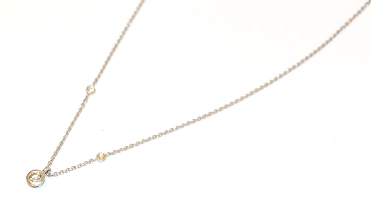 A diamond pendant on chain, the round brilliant cut diamond in a white rubbed over setting, on a