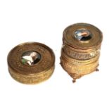 A brass trinket box with musical movement and another box, each set with a porcelain plaque, each