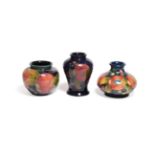 Three William Moorcroft Pomegranate pattern vases, on blue grounds, factory marks, 7cm, 7.5cm and