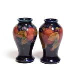 Two William Moorcroft Pomegranate pattern vases, on blue grounds, impressed marks, 10cm (restored)