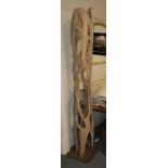 A cylindrical drift wood sculpture on metal square base