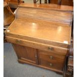 A circa 1920's oak writing desk, the drawer connected to a tambour mechanism, opening to reveal a