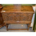 A 20th century carved oak chest with a hinged lid above carved panels and turned legs, 79cm by