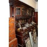 An imposing ornately carved sideboard, the upper section with leaf and scroll carved broken pediment