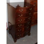 A reproduction serpentine fronted six height chest of drawers