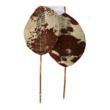 Two 20th Century Zulu Cow Hide Shields, each of tan and white colouring, of elliptical form,