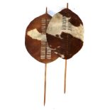 Two 20th Century Zulu Cow Hide Shields, each of tan and white colouring, of elliptical form,