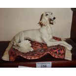 A Continental porcelain figure of a Saluki on a Persian rug