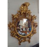 Italian giltwood rococco style circular wall mirror, the frame 19" x 15" overall, with foliate