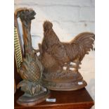 Two cast iron doorstops, one pineapple and one chicken/rooster