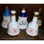 Five Wade china decanters full of Bell's Whisky