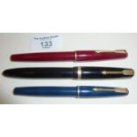 Three Parker fountain pens with gold nibs, a maroon Parker 17, a black Maxima Duofold and a blue