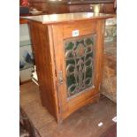 Art Nouveau mahogany single door wall cabinet having green glazed door with fretwork copper overlay