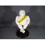 A cast iron novelty advertising figure of a Michelin man in a seated position on a swivel chair