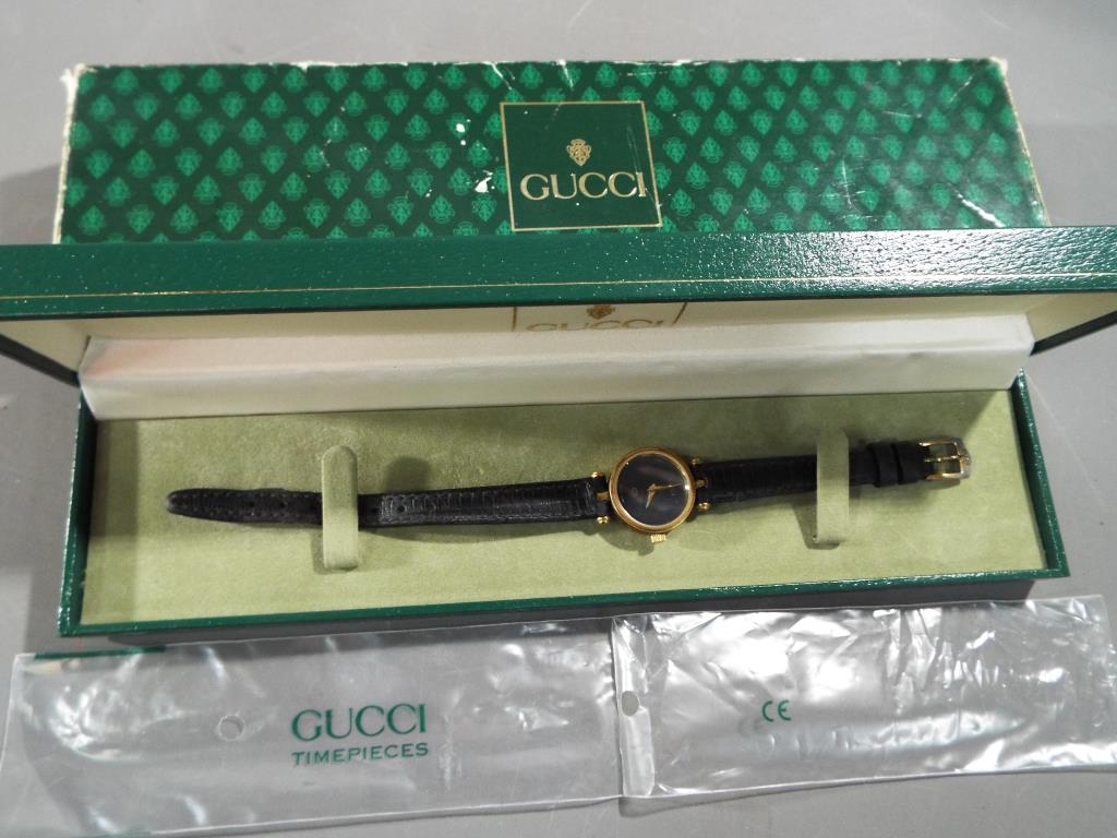 Gucci - a lady's designer Gucci Swiss made wristwatch with leather strap black Gucci face with