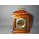 An Elliott mantel clock in a walnut veneer case with brass carrying handle,