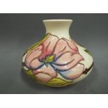 Moorcroft Pottery - a large squat vase decorated with depictions of pink magnolia on an ivorine