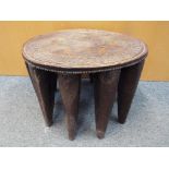 A Nigerian Nupe stool, oval top with carved geometric decoration on ten supports,
