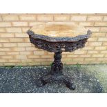 A 19th century tripod table profusely carved with floral and foliate decoration,