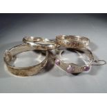 Four hallmarked silver bangles all with safety chain and scrolled decoration.