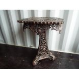 An unusual metal round topped table with intricate foliate and scrolled pierced decoration