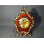 A small desk or mantel clock in a polished mahogany case with Rococo-style brass mounts,