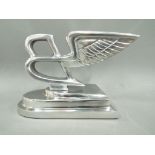 A white metal winged 'B' in the style of a promotional Bentley sign on base,