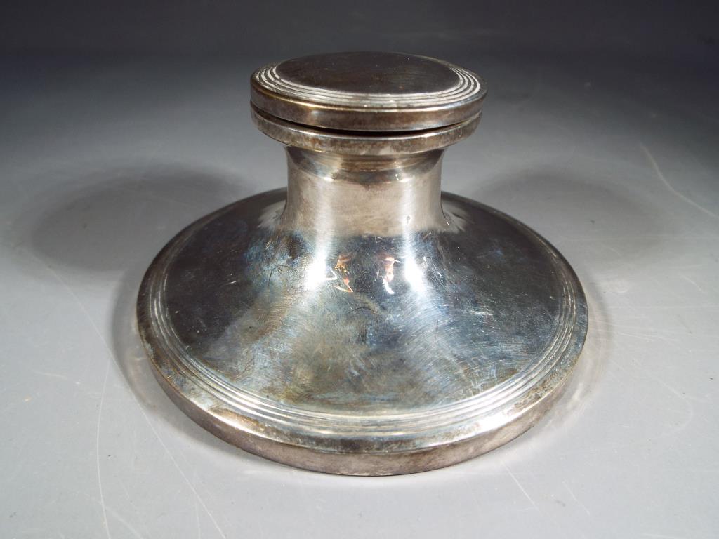 An Edward VII silver hallmarked capstan inkwell with hinged lid and glass vessel,
