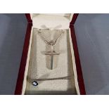 A silver crucifix and chain and a promotional BMW pin badge