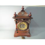 A German Black Forest wooden cased mantel clock with turned finials and applied brass decoration,