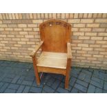 An oak armchair with carved decoration to the back rest.