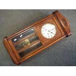 An oak cased wall clock, Roman numerals to the dial, with key and pendulum.