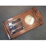 An oak cased wall clock, Arabic numerals to the dial, with key and pendulum.
