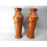 A pair of wooden vases, decorated with applied roundel motifs, approximately 34 cm (h).