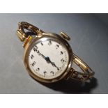 A lady's vintage yellow metal wristwatch, Arabic numerals to the white dial,