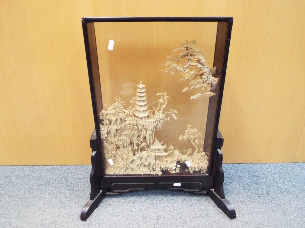 A Chinese carved cork landscape diorama in glazed case, raised on a stand,