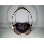 An Art Nouveau basket centerpiece decorated with floral motifs with iridescent blue glass liner.