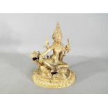 A 19th century gilt bronze figure depicting Manjushri / Shiva seated on a lion,