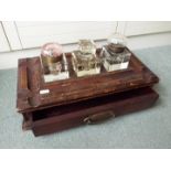 A Victorian wooden inkwell stand containing three ink wells