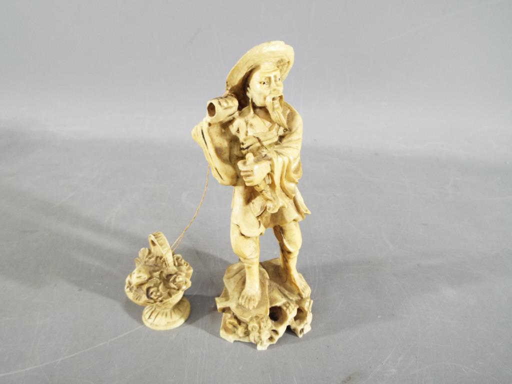 A oriental figurine of a fisherman carrying a basket