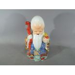 A 20th century Chinese Doaist famille rose figurine depicting Shou Lao holding staff and peach,