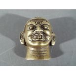 A small gilt bronze Buddha mask, approximately 4.5 cm.