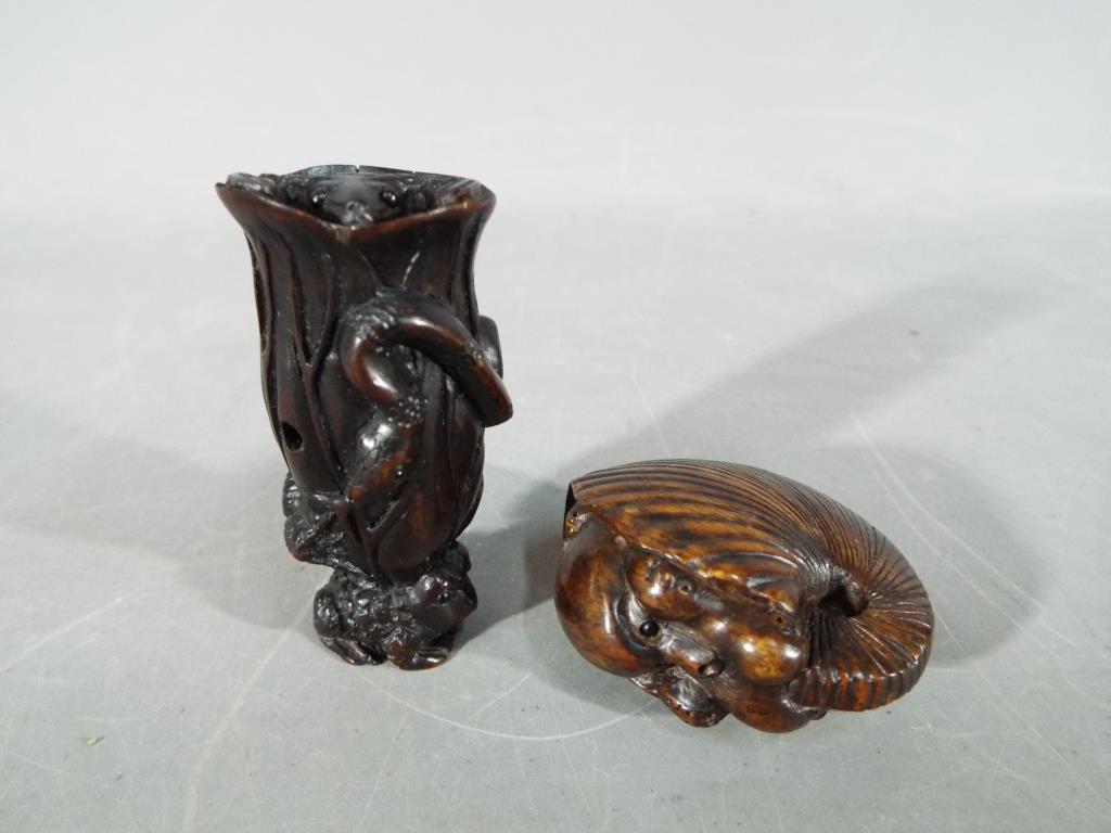 A vintage dark wood Netsuke depicting a small frog type animal carrying a large tree trunk on its