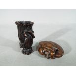 A vintage dark wood Netsuke depicting a small frog type animal carrying a large tree trunk on its