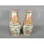 A pair of Chinese 19th century Canton famille rose vases with everted rim (small chips to one rim),