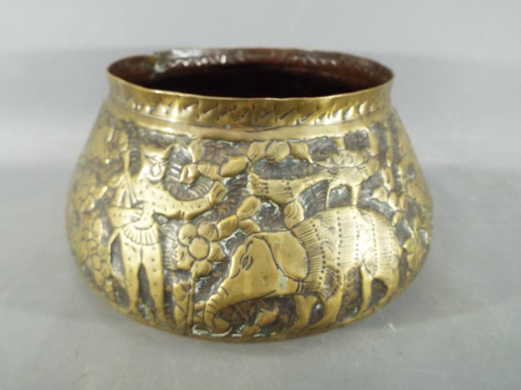 A middle eastern gilt bowl with repoussé decoration depicting fauna and mythical creatures,