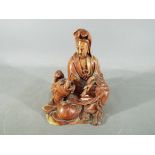 A 19th Chinese soapstone carving depicting Guanyin dressed in flowing robes and holding a scroll,