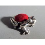 A silver pin cushion in the form of a frog