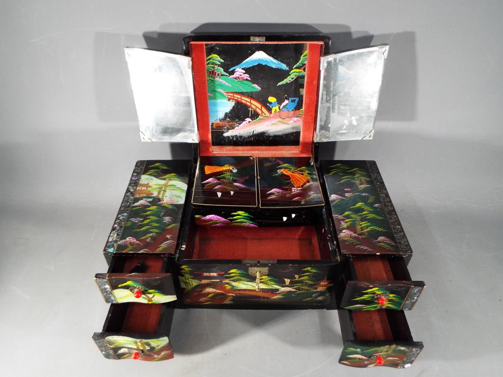 A Japanese lacquered, musical jewellery box with hand painted landscape decoration,